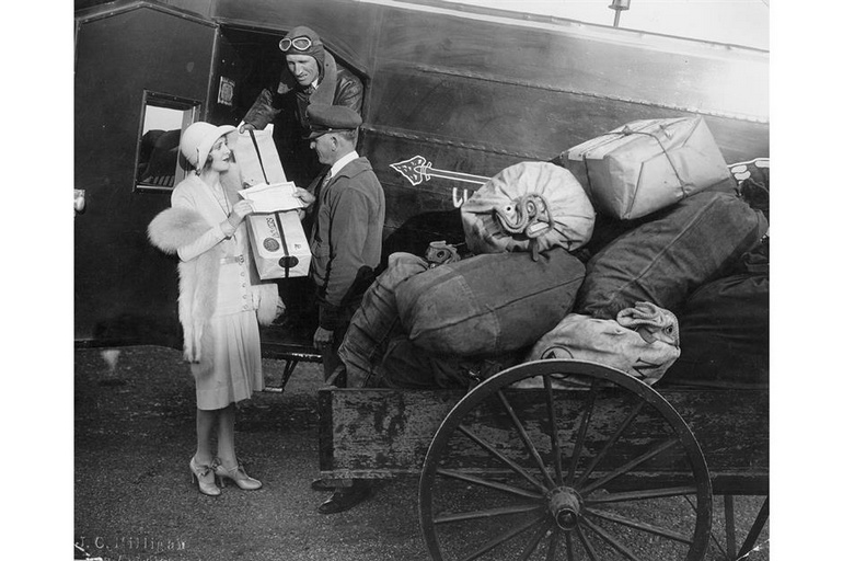 Une femme remet un colis postal aérien au personnel de Western Air Express, vers 1930